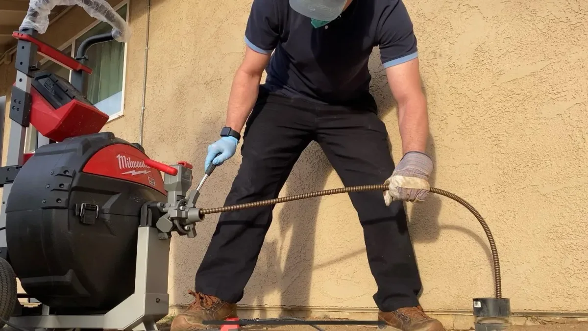Plumber operating a drain-cleaning machine